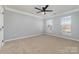 A bedroom with neutral paint, ceiling fan, large windows and soft carpet provides a serene and relaxing space at 1245 Periwinkle Dr, Waxhaw, NC 28173