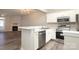 Bright, open kitchen with stainless steel appliances, white cabinets, and a view of the living room fireplace at 14713 Lions Pride Ct, Charlotte, NC 28273