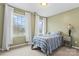 Sunlit bedroom with two windows, soft green walls, and a cozy bed with a gray and blue patterned comforter at 1511 35Th Ne Ave, Hickory, NC 28601