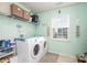 Well-organized laundry room with modern washer and dryer, shelving, and natural light at 1535 Scarbrough Sw Cir, Concord, NC 28025