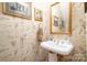 Powder room featuring unique wallpaper, a pedestal sink, and gold fixtures at 286 Canvasback Rd, Mooresville, NC 28117