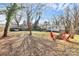 Large backyard with a fire pit, red Adirondack chairs, and a well-maintained lawn at 302 Digh St, Gastonia, NC 28052