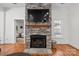 Elegant stone fireplace with mounted TV, a wooden mantel, and hardwood floors enhancing the room's ambiance at 4008 Saint Andrews Ct, Cramerton, NC 28032