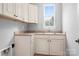 Functional laundry room with cabinets, a sink, and a window for natural light and ventilation at 7191 Grist Mill Ct, Denver, NC 28037