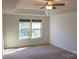 Serene bedroom with neutral carpet, tray ceiling with ceiling fan, and windows with peaceful views at 8471 Penton Pl, Harrisburg, NC 28075