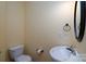 Cozy half bathroom featuring a toilet, sink, and a dark framed circular mirror at 8471 Penton Pl, Harrisburg, NC 28075