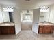 Main bathroom with double vanities, framed mirrors, sconces, and a connecting bedroom featuring a ceiling fan and window at 8471 Penton Pl, Harrisburg, NC 28075