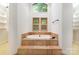 Relaxing bathroom featuring soaking tub with stone surround and bright windows at 1006 Lost Cv, Weddington, NC 28104