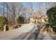 Long gravel driveway leads to a brick home nestled among mature trees, offering privacy and curb appeal at 1006 Lost Cv, Weddington, NC 28104