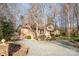 Long gravel driveway leads to a brick home nestled among mature trees, offering privacy and curb appeal at 1006 Lost Cv, Weddington, NC 28104