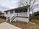 A side view of a cozy one-story house with white trim and a cute lattice-covered porch at 117 Cove Ave, Mount Holly, NC 28120