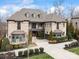 Stately stone home boasts refined design, including manicured landscaping, bay windows, and a welcoming driveway, all under a bright sky at 1238 Ladera Dr, Waxhaw, NC 28173