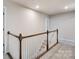 Bright hallway featuring neutral carpet and wood railing at 14726 Tamarack Dr, Charlotte, NC 28278