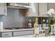 Close-up of a kitchen featuring a modern backsplash, gas range, and white cabinets at 1498 Hubert Graham Way, Tega Cay, SC 29708
