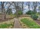 Lush backyard featuring a fire pit, brick pathway, mature trees, and new wood fence at 3126 Creighton Dr, Charlotte, NC 28205