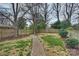 Well-maintained backyard with a stone fire pit area, brick pathway, and new wood fence at 3126 Creighton Dr, Charlotte, NC 28205