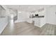 Open-concept living room with gray wood floors, modern lighting, and an adjacent kitchen space at 6814 Piper Thorn Way, Indian Land, SC 29707