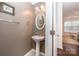 Well-lit powder room with a pedestal sink, oval mirror, and neutral wall paint at 706 Cherryfield Pl, Rock Hill, SC 29732