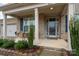 Inviting front porch featuring a seating area, manicured shrubs, and a brick facade for a warm welcome at 8651 Shadetree St, Huntersville, NC 28078