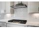 Close up of a cooktop with a stainless steel range hood in a modern white kitchen at 8720 Acadia Pkwy # 597, Sherrills Ford, NC 28673