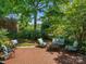 Large brick backyard patio under the shade of large trees, featuring multiple seating areas and greenery at 9743 Aegean Ct, Huntersville, NC 28078