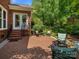 Wide-angle view of brick backyard patio with multiple chairs and a view of the lush treeline at 9743 Aegean Ct, Huntersville, NC 28078