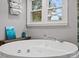 Close-up of a soaking tub with window view and a stand-up shower with glass doors at 9743 Aegean Ct, Huntersville, NC 28078