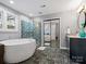 Spa-like bathroom features a jetted tub, glass shower and stylish black tile floors at 9743 Aegean Ct, Huntersville, NC 28078