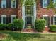 Close up of the brick two-story home's front entrance with a large window and green manicured bushes at 9743 Aegean Ct, Huntersville, NC 28078