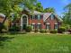 Beautiful brick two-story home featuring a large front yard, manicured bushes, and many windows at 9743 Aegean Ct, Huntersville, NC 28078