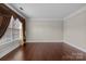 A bright and spacious living room features hardwood floors and large windows with decorative curtains at 12515 Hashanli Pl, Matthews, NC 28105