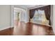 Open-concept living area with hardwood flooring and decorative curtains creating an inviting space at 12515 Hashanli Pl, Matthews, NC 28105