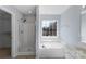 Bright bathroom featuring a soaking tub under a window, a glass door shower, and tile floors at 152 Painted Bunting Dr, Troutman, NC 28166