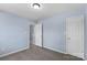 A neutral-toned bedroom with two access doors, featuring plush carpet and plenty of natural light at 152 Painted Bunting Dr, Troutman, NC 28166