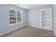 Bright bedroom with a large window, built-in bookcase, neutral walls and plush carpet at 152 Painted Bunting Dr, Troutman, NC 28166