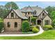 Stunning two-story home with a turret, brick and stone facade, professional landscaping and a winding walkway to the front door at 16824 Ashton Oaks Dr, Charlotte, NC 28278
