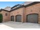 Spacious three-car garage with brick exterior, featuring arched doors and stylish lighting fixtures at 16824 Ashton Oaks Dr, Charlotte, NC 28278
