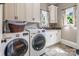 Functional laundry room with white cabinets, granite countertops, and modern washer and dryer at 16824 Ashton Oaks Dr, Charlotte, NC 28278