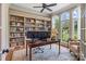 Bright office featuring custom built-ins, hardwood floors, a ceiling fan, and natural light from large windows at 16824 Ashton Oaks Dr, Charlotte, NC 28278