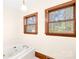 Bathroom featuring a soaking tub with jets, wood trim, and natural light from two windows at 171 Agnew Rd, Mooresville, NC 28117