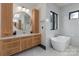 Bright bathroom showcasing a soaking tub, natural wood vanity with marble counters and a round mirror at 180 Willow Point Rd, Troutman, NC 28166