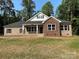Charming brick and stone home featuring a covered porch, black shutters, and a well-manicured lawn at 309 General As Johnston St, Stanley, NC 28164