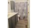 Bathroom features a shower with curtain, wood floors, gray vanity and toilet at 3640 Muskrat Se Pl, Concord, NC 28025