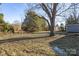 View of the front yard of the property showing mature trees and a storage shed at 445 Cannon Farm Rd, China Grove, NC 28023