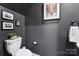 Elegant powder room features charcoal gray walls, framed artwork, stylish fixtures and a white porcelain toilet at 6509 Gopher Rd, Lancaster, SC 29720