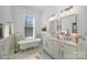 A bathroom featuring marble tiled floors and wall, modern vanity with gold hardware, tub, and natural light at 116 Rose Ter, Wadesboro, NC 28170