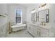 A bathroom featuring marble tiled floors and wall, modern vanity with gold hardware, tub, and natural light at 116 Rose Ter, Wadesboro, NC 28170