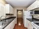 Galley kitchen with stainless steel sink, white appliances, and dark countertops at 1323 Queens Rd # 308, Charlotte, NC 28207