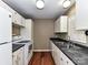 Galley kitchen with white cabinets, black countertops, and stainless steel appliances at 1323 Queens Rd # 308, Charlotte, NC 28207