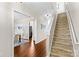 Hallway with wood floors leads to carpeted stairs, dining room, and kitchen at 14462 Holly Springs Dr, Huntersville, NC 28078